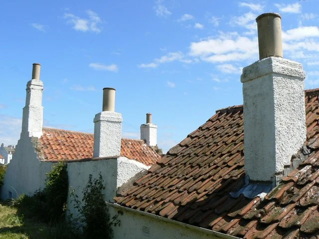 Red-brown clay pantiles on cottages above Crail Harbour, with white chimneys and eaves guttering.