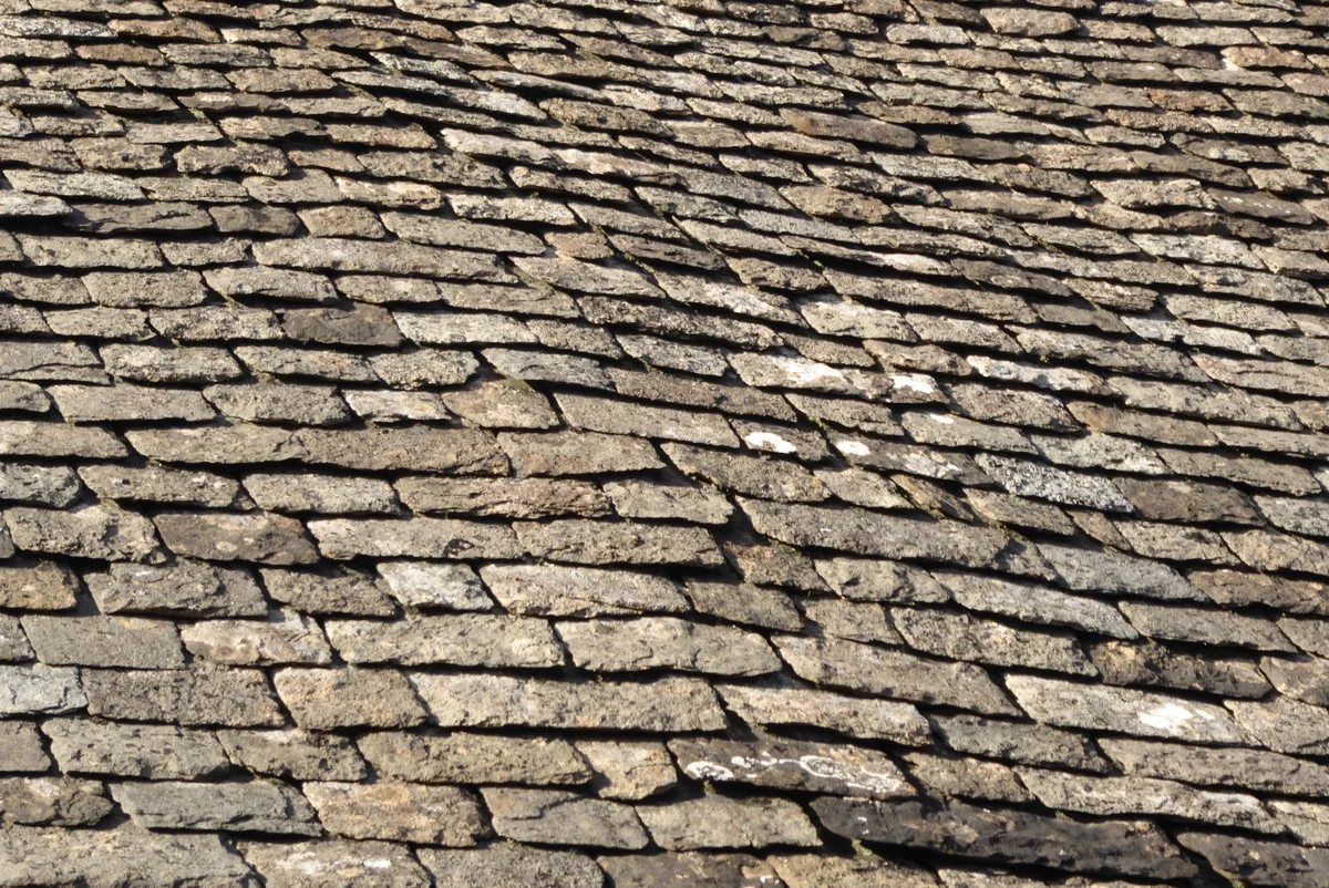 Close view of irregular Cotswold stone slates in overlapping courses on a roof in Fairford, Gloucestershire.