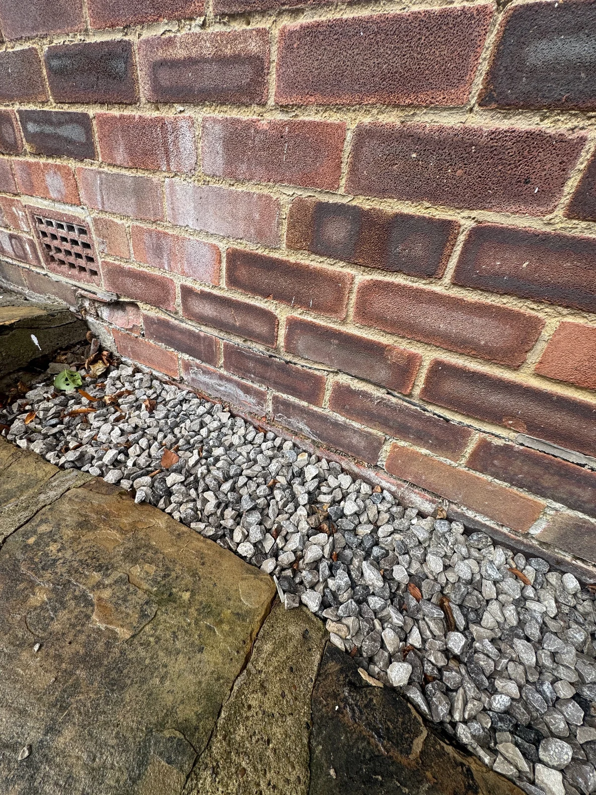 White surface deposits and local spalling on low-level brickwork.