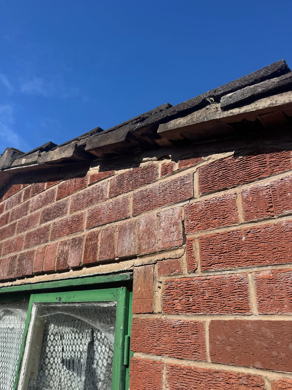 Cracks following masonry joints above an older window.
