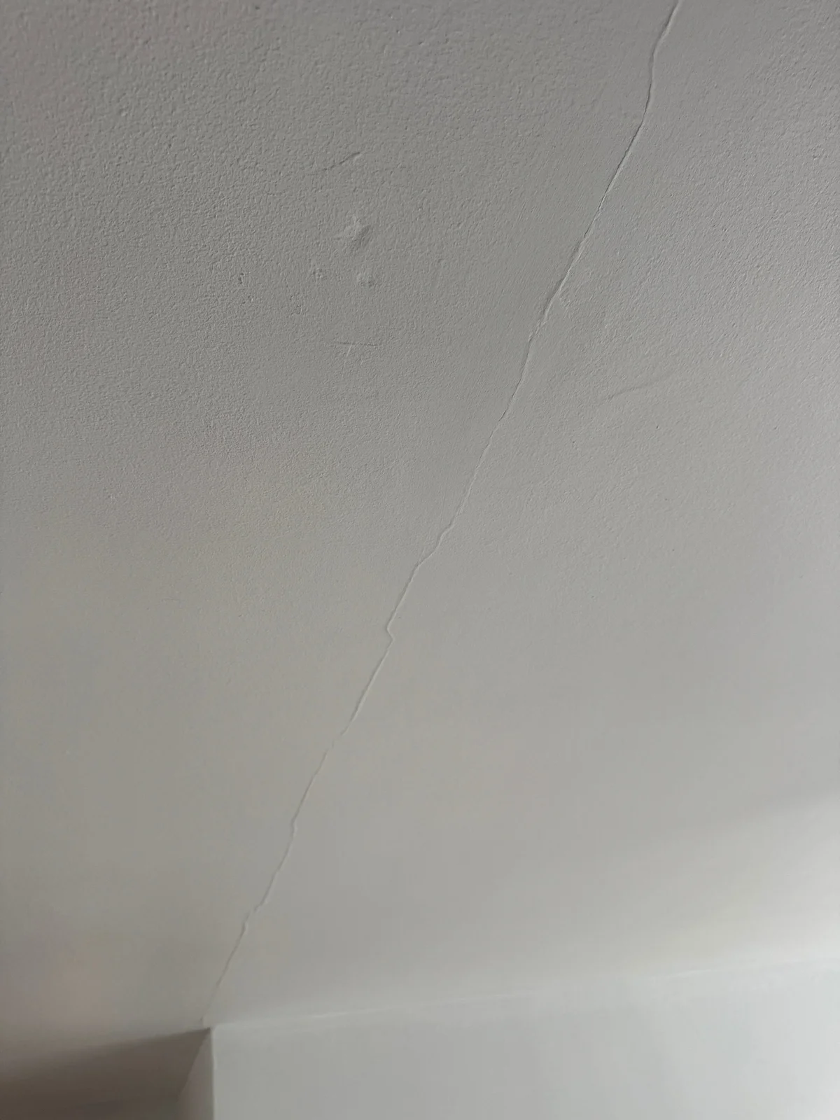 A narrow crack following a ceiling joint.
