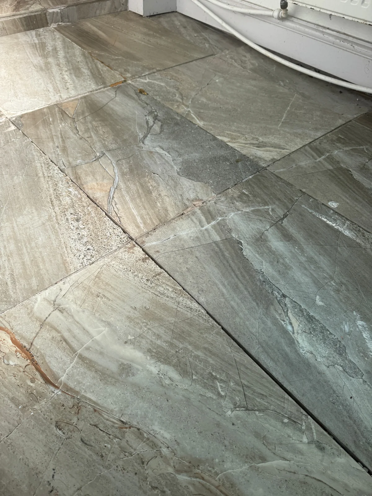 An open joint between adjacent floor tiles, viewed at floor level.