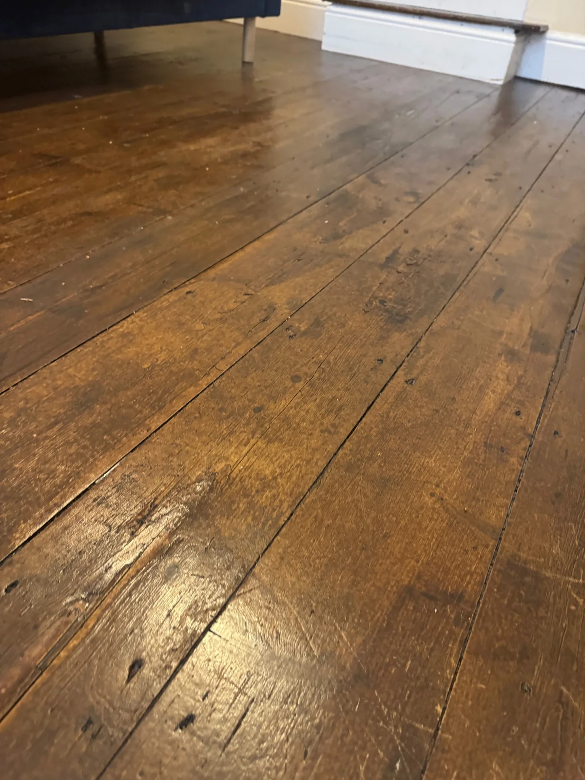 Brown finished floorboards with visible joints, fixings, wear and local marks.